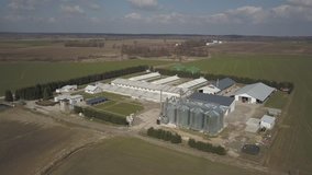 The view from the height of a large farm located among the green hilly fields. Video from a drone or a quadro. Agro-industrial complex with stainless steel silo. Organic food production.Dairy industry