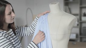 The slow motion video of designer of clothes works with a dummy in sewing agency, the size is 46, hands of the master in sewing with blue fabric, sewing needles with a red tip, 120 fps