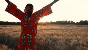 
HD Video clip of African woman farmer arms raised celebrating in traditional clothes standing in a farm field of crops in Africa at sunset or sunrise
