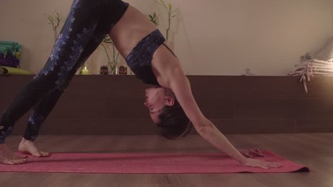 Young flexible woman practicing yoga indoors. Crane shot