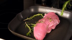 Cook placing sprigs of fresh rosemary onto chicken