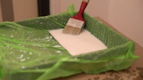 Person filling a painting tray with white paint