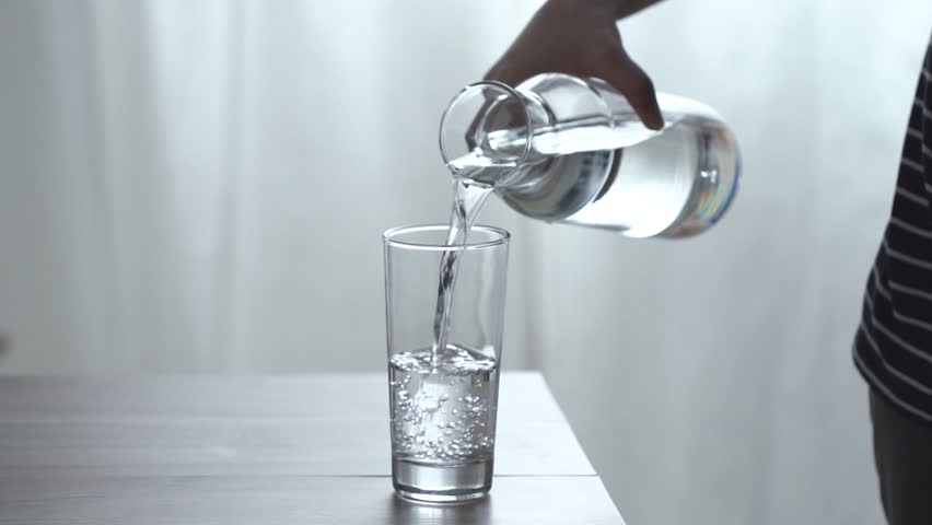 Woman's hand pouring fresh pure water from bottle into a glass on the table, health and diet concept, Slow motion footage | Shutterstock HD Video #1026238922