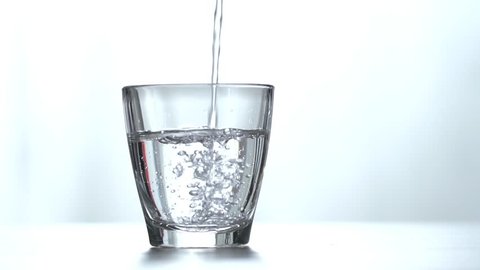 Pouring fresh pure water from bottle into a glass on the table, health and diet concept, Isolate on white background, Slow motion footage