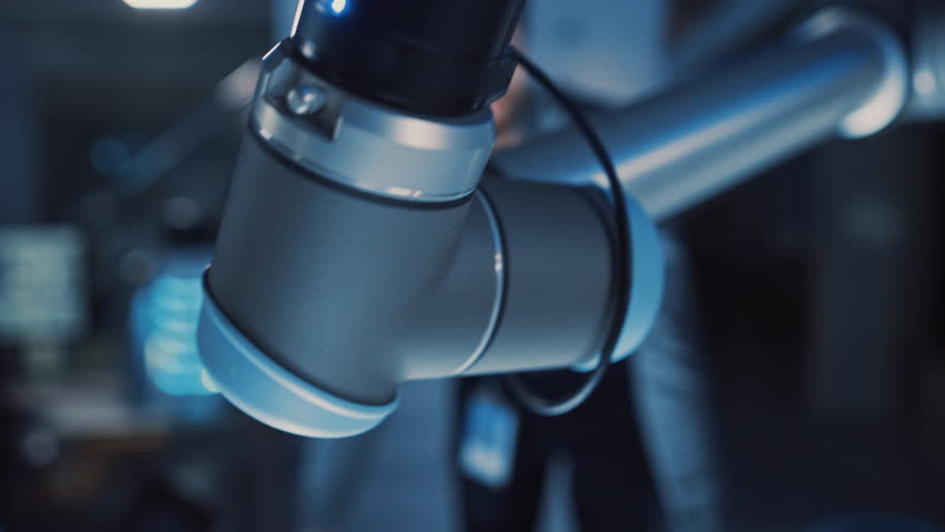 Close Up of a Futuristic Robotic Arm Moving a Metal Object and Placing It. Team of Engineers Observe This Advanced Process. They are in a High Tech Research Laboratory with Modern Equipment. Royalty-Free Stock Footage #1026242000