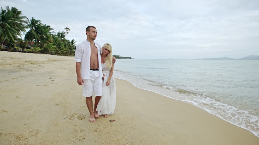 Loving couple walking arm in arm along a beach