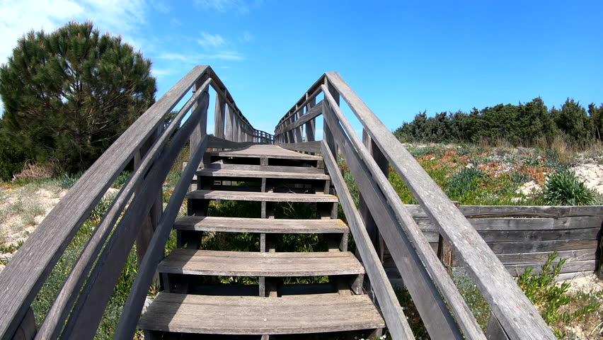 Walking on a wooden footbridge toward the beach in spring