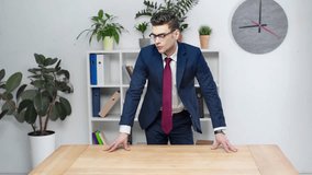 handsome businessman looking at new wooden empty desk in office
