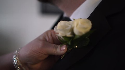 Mother helping her son pin on a boutonnière for his wedding Stockvideó