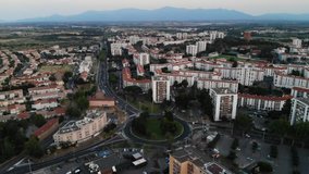 Aerial Drone Footage of a Roundabout and Apartment Buildings the City of Perpignan with the Pyrenees-Orientales Mountains in the Background in the South of France