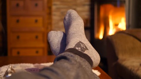 Feet with socks close up with orange bright fire burning in the background warm, relaxed and cozy inside on a winters night วิดีโอสต็อก