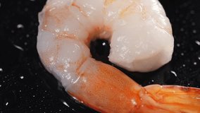 Shrimp is lying on a black table. Water is poured onto the shrimp in slow motion. Food video. Video for restaurant and cafe.