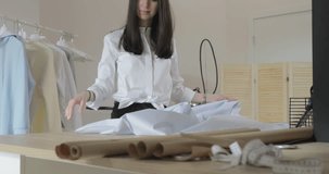 Slowed-down video of that as the young long-haired girl spreads fabric on a table for dressmaking in sewing salon