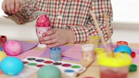 Happy child wearing bunny ears painting eggs on Easter day. Little boy preparing for the Easter. slow motion