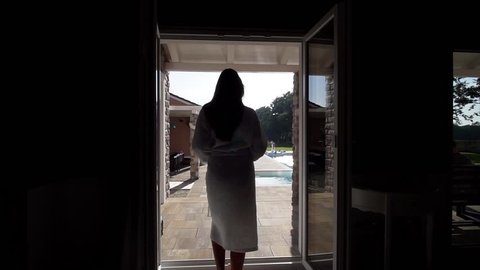 Beautiful woman walks to villa pool, calling you to join before throwing robe wide to enter pool