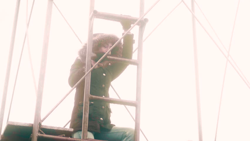 A woman climbs to the top of a metal outpost structure to stand guard, 30 fps.