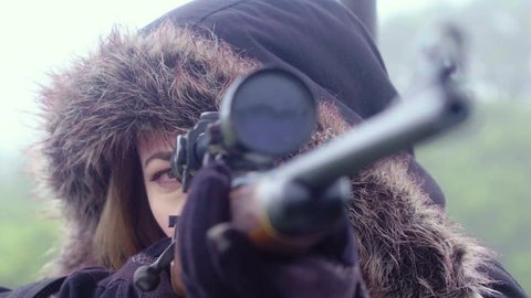 Close up of a woman patiently waiting and watching through the telescopic scope of a rifle, 30 fps.
