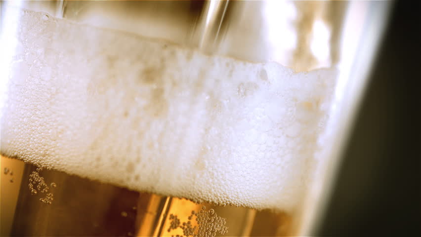 Beer is pouring into angled glass. IPA on tap. Cold Light Beer in a glass with water drops. Craft Beer forming waves close up. Freshness and froth. Bar background. Microbrewery craft beer. | Shutterstock HD Video #1026296498