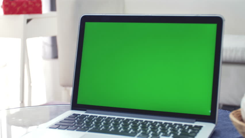 Laptop Computer Showing Green Chroma Key Screen Stands on a Desk in the Living Room. In the Background Cozy Living Room. Dolly Zoom out Shot. 4K Royalty-Free Stock Footage #1026300152