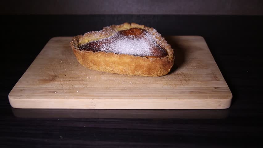 Pouring sugar on heart shaped cheesecake close up shoot