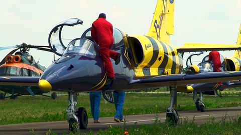 Krasnodar, Russia, June 15, 2013: Mechanics in red overalls install stoppers on ejection seats of Baltic Bees group training aircraft L-39 before disembarking pilots from cockpit.