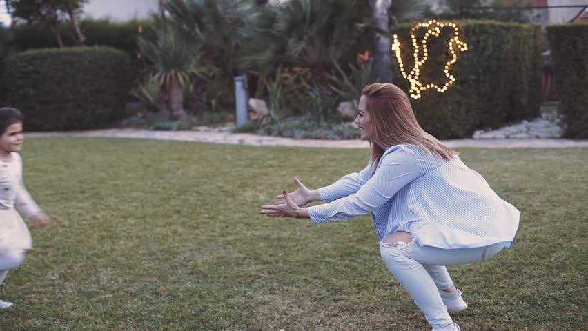 cute daughter running and jumping on her mother