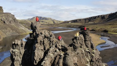 Aerial drone shot of people sitting on a cliff revealing a river in Highlands of Iceland
