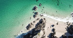Beautiful drone aerial shot flying over fisherman's lookout Byron Bay Australia with aqua waves rolling in from the ocean and crashing against natural rocks.