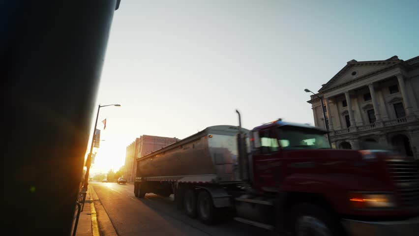 A semi driving by revealing a sunrise courthouse scene in a small city
