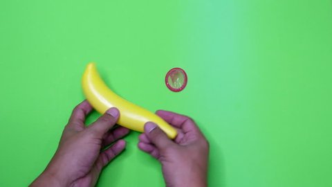 The male hand is demonstrating wearing a condom. By using banana toys instead of the penis On a green background