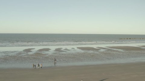 A travelling of the sea at Dunkirk beach in France (Dunkerque in French). There are somes people and seagulls.