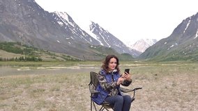 Woman tourist with a mobile phone talking on the video link. against the backdrop of the mountains