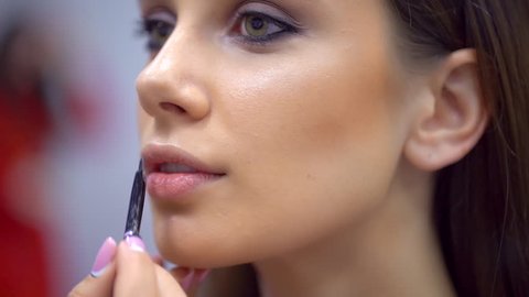 fashion show, visagist working, making professional make up backstage. face of pretty girl beautiful woman model. Make up artist applying stylish makeup lips to young female, visage beauty contest 4 K