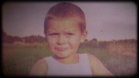 Family video archive. Retro camera 8 mm. Old film. Vintage. Portrait of a shy 4-year-old kid against a background of nature, the child looks into the camera and smiles, then looks away
