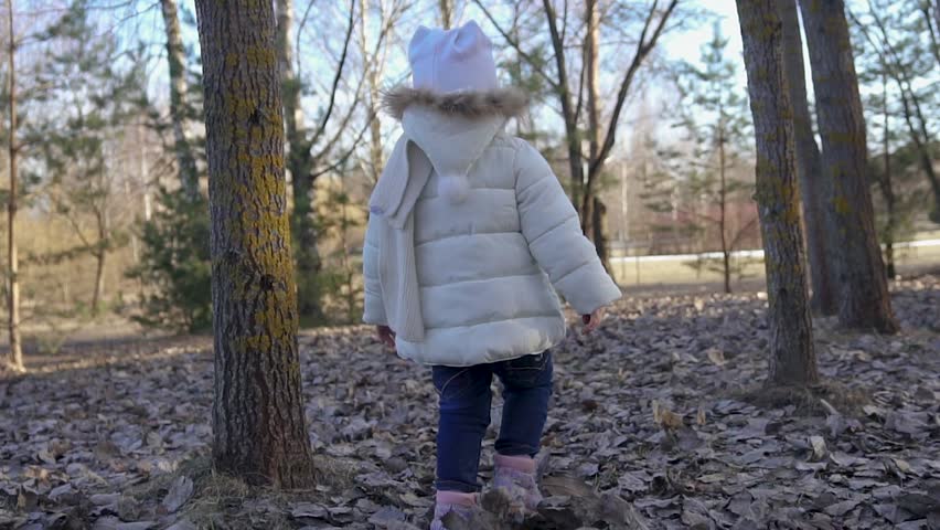 Happy little girl rejoices in the arrival of spring. She runs across the field. View from the back. Slow motion.