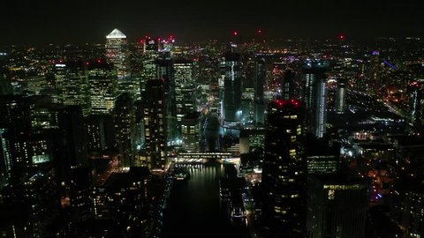 Docklands, London / United Kingdom - March 18 2019: Aerial bird's eye panoramic night video taken by drone of iconic Canary Wharf skyscraper complex and business district, Isle of dogs