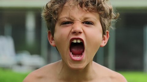 Child boy screaming from top of his lungs in slow-motion 120fps. Kid yelling roaring to camera