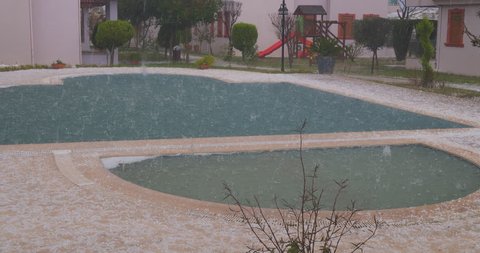 Hail in a summer storm. Ice balls heavily hit the swimming pool