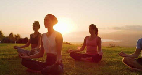 Zen meditation practice at sunset, group of diverse young people meditating together at sunset, zen health and wellness