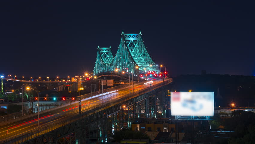 Big city traffic travelling over the Jacques Cartier bridge in Montreal Quebec at night. Long exposure light trails show a fast paced city.