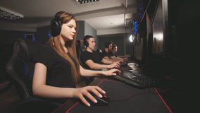 Team of gamers in headphones emotionally rejoices in victory playing in e-sport club, looks at the computer screen and enjoying their triumph.
