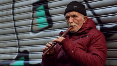 Istanbul \ Turkey - July 7 2017: Senior old man playing the flute outdoors on the city street. Musician, talent, romantic atmosphere. Making money, profession concept