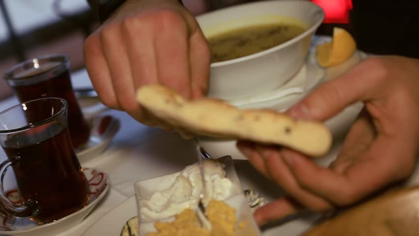Close up view of male hands smearing traditional sauce on Turkish bread called pide. Having dinner, restaurant, cuisine. Being a gourmet, food tourism. Having fun