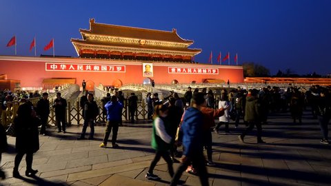 BEIJING - MARCH 23, 2018: Unidentified tourists walk against Tiananmen gate, take pictures at evening time, after flag haul down ceremony. Many people at sidewalk, illuminated Gate of Heavenly Peace