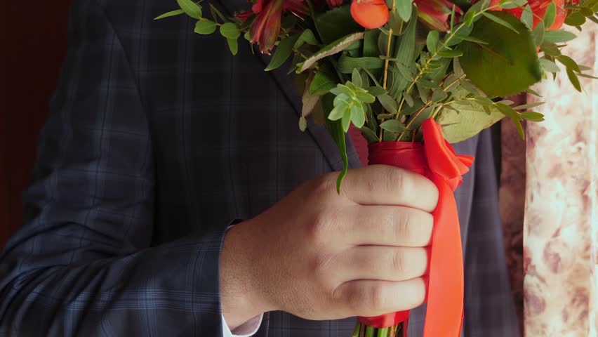businessman with beautiful flowers. beautiful bouquet of red roses in hands of men in jacket in red tie and white shirt. close-up.
