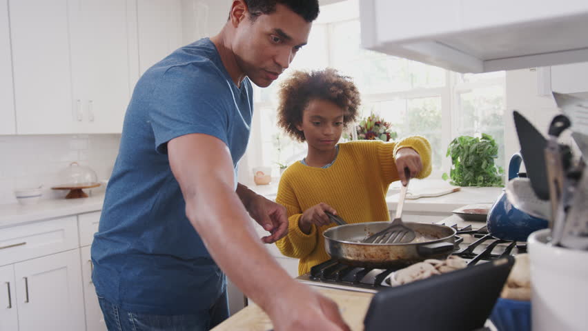 Pre-teen black girl and her father preparing food following a recipe on a tablet computer, close up Royalty-Free Stock Footage #1026410147