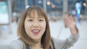 Slow motion - Young Asian backpacker blogger woman using camera making vlog video while waiting for flight, female standing in terminal hall in international airport. Lifestyle woman travel concept.