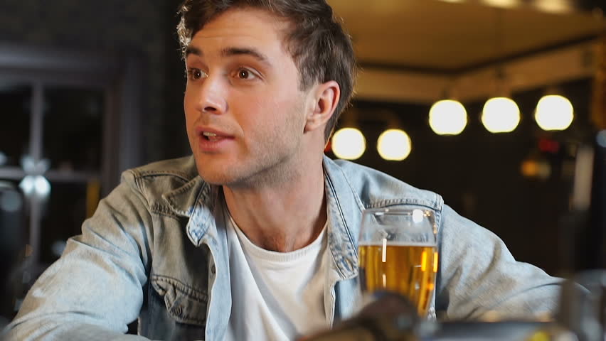 Friends watching sports game in pub, drinking fresh beer, disappointed with loss | Shutterstock HD Video #1026418550