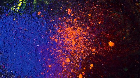 Top view of beautiful, bright colored powder falling and mixing. Dry orange and blue inks falling down on black background, art concept.