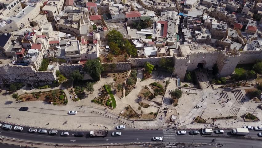 Symmetrical aerial view of the Damascus Gate, city walls, promenade, streets and houses of the Muslim Quarter of Old City Jerusalem.